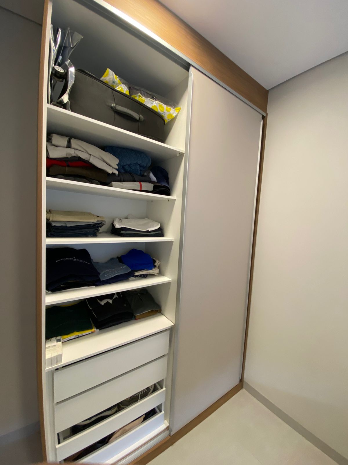 Guarda-roupa planejado com portas de correr em tom neutro e moldura em madeira