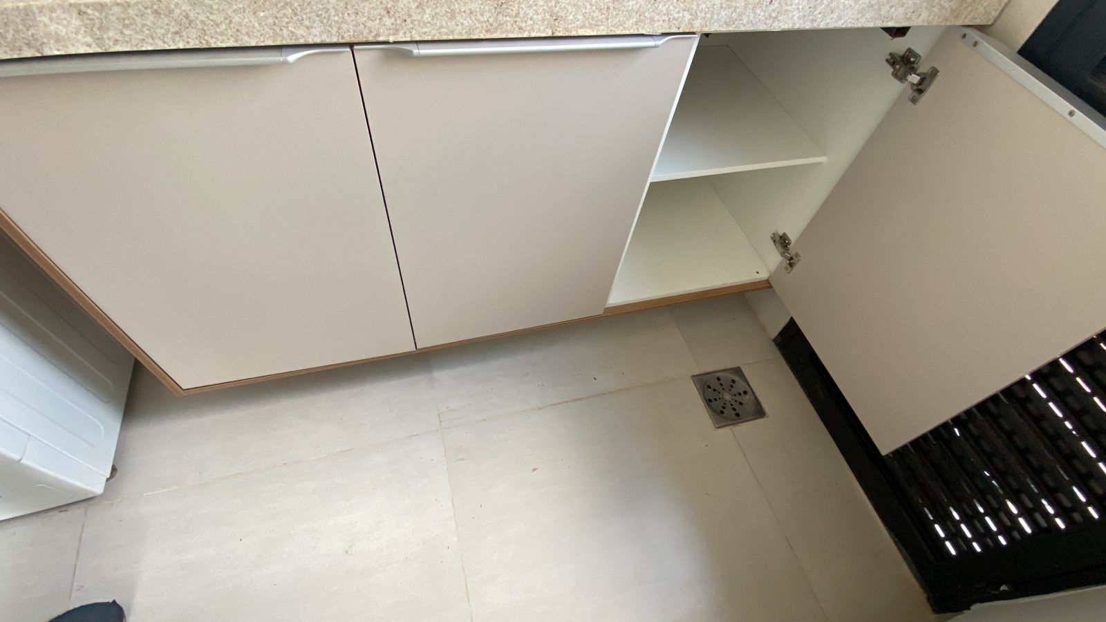 Armário inferior de lavanderia com portas em tom neutro e puxadores minimalistas