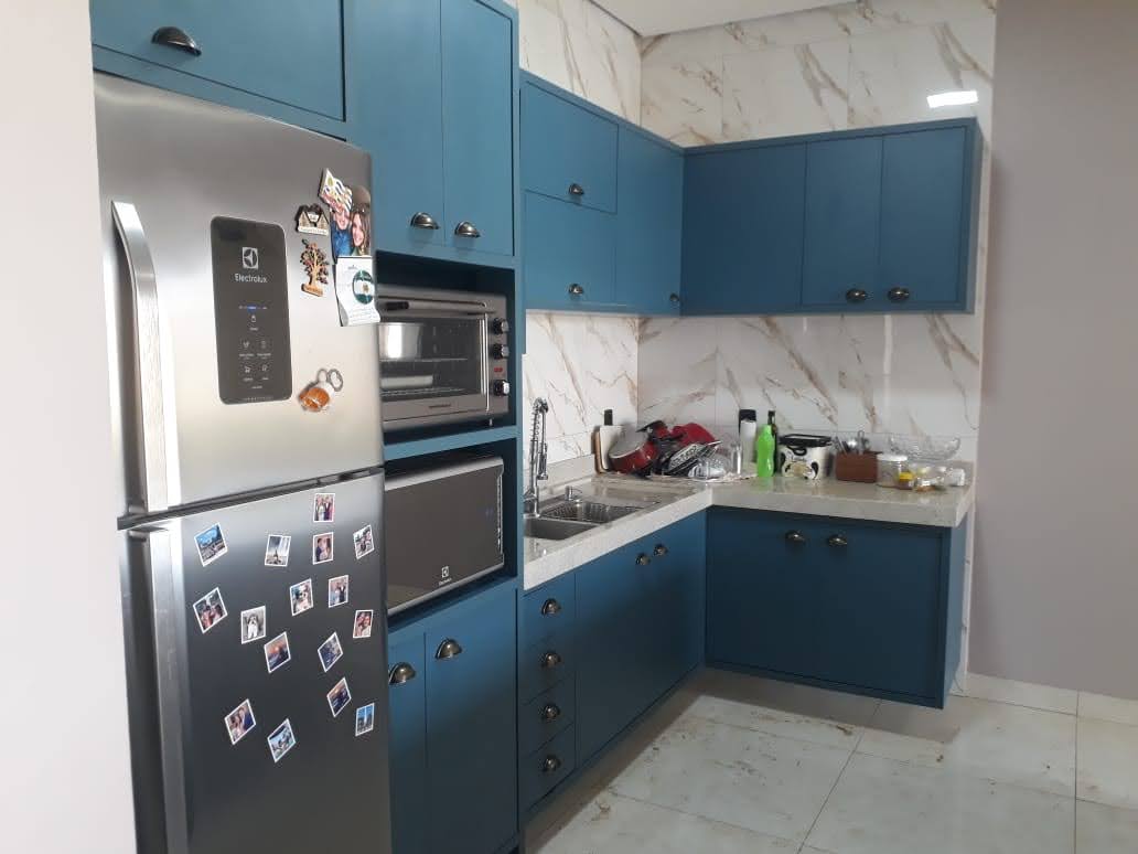 Canto da cozinha planejada azul com bancada, cuba, armários e composição em L