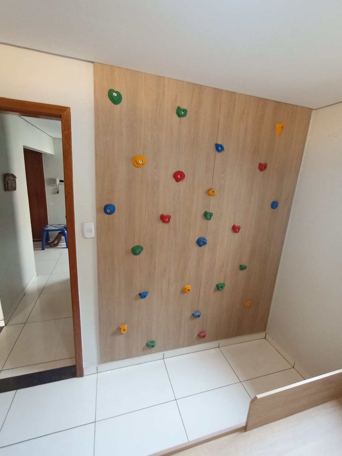 Cozinha compacta com painel ripado, armários em madeira, bancada em L e iluminação embutida