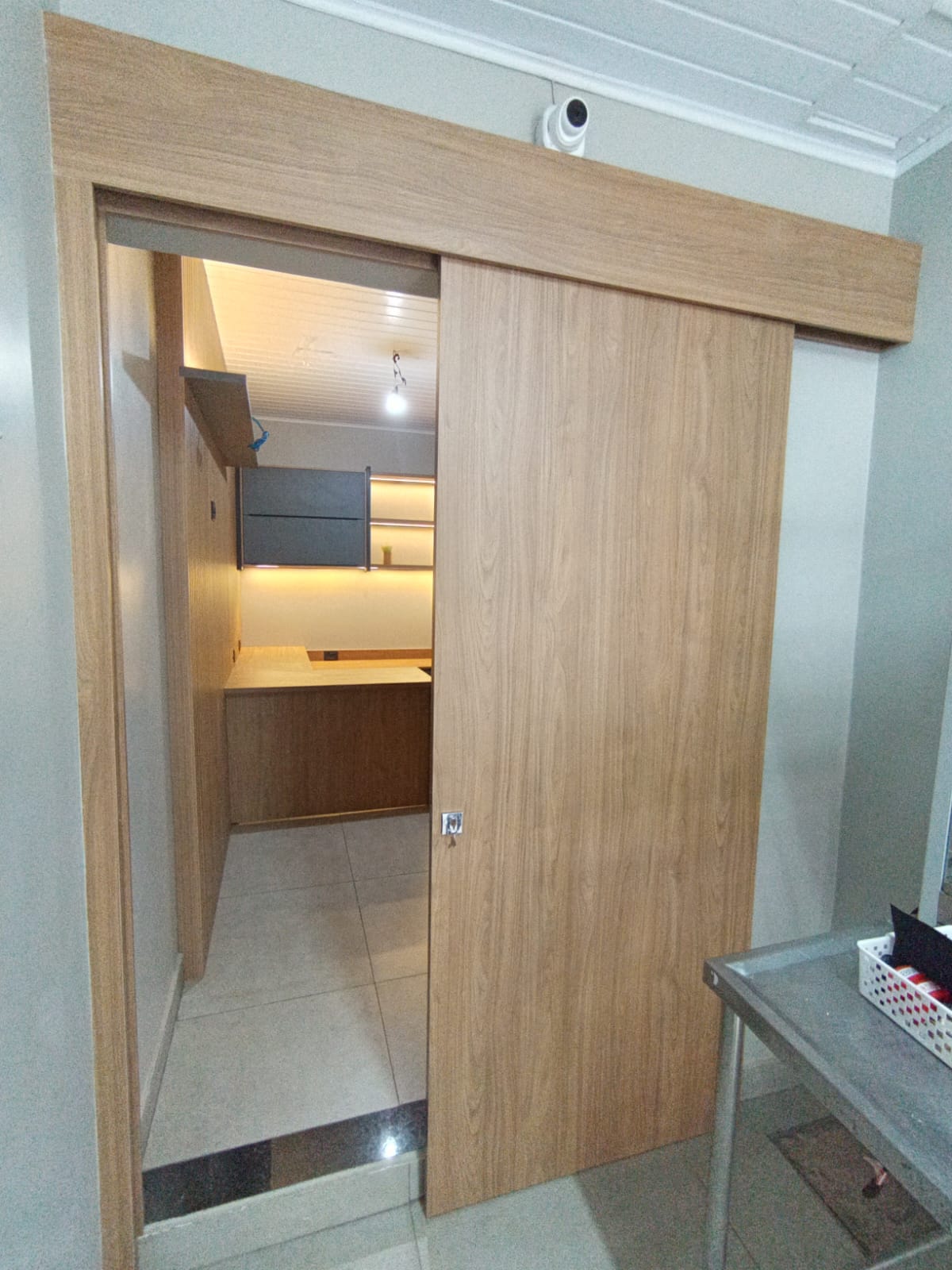 Porta de correr em madeira revelando home office planejado com marcenaria sob medida