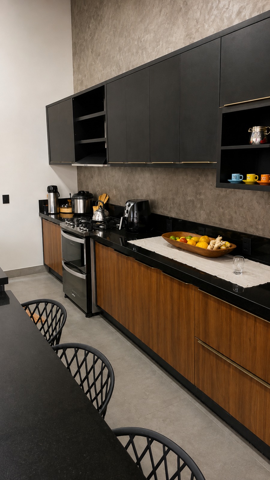 Vista lateral de cozinha planejada com armários pretos, bancada preta e marcenaria sob medida