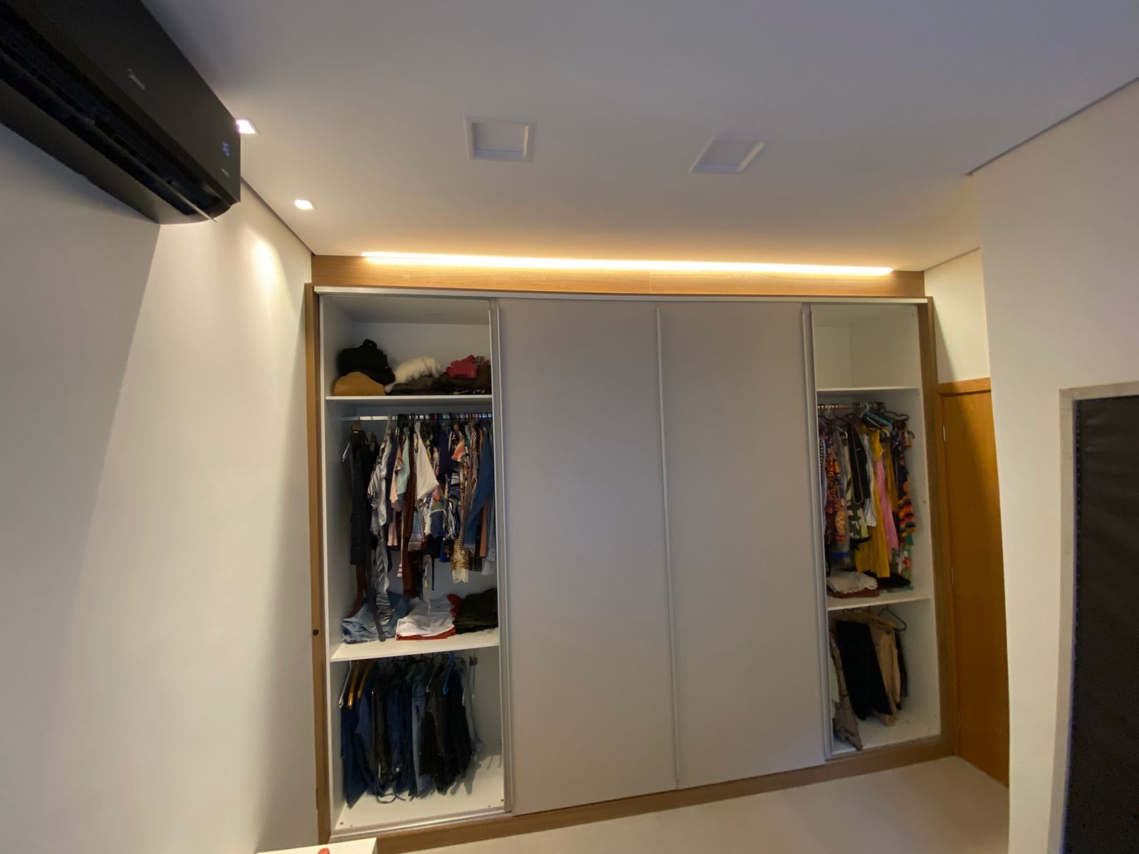 Guarda-roupa planejado com portas de correr abertas, exibindo divisões internas para roupas
